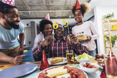 Multi-Generation african american family celebrating grandfathers birthday at home together