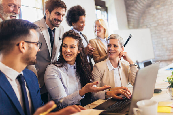 Group of young confident business people analyzing data using computer while spending time in the office
