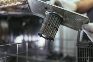 Male Technician Repairing Dishwasher In Kitchen, close up. Dishwasher filter