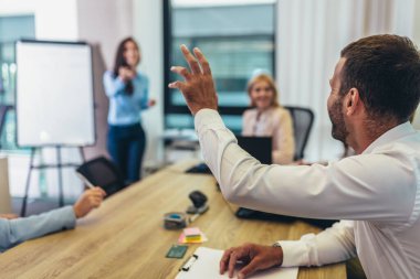 Businessman raising her hand to ask the question on a seminar in board room.