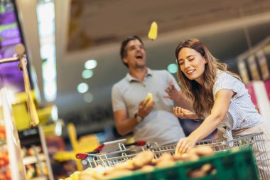 Beautiful young smiling couple choosing fruits in supermarket together