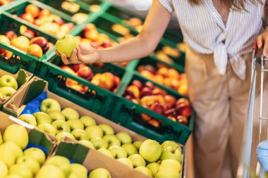 Woman In Supermarket Choosing Fresh Fruits, close up.