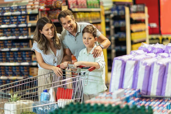 Çocuklu ve alışveriş arabalı mutlu bir aile marketten ya da marketten yiyecek alıyor.