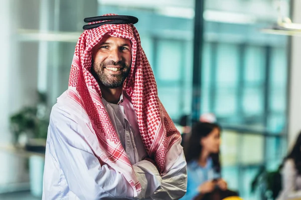 Portrait of Arabian smiling man with traditional wear in office.
