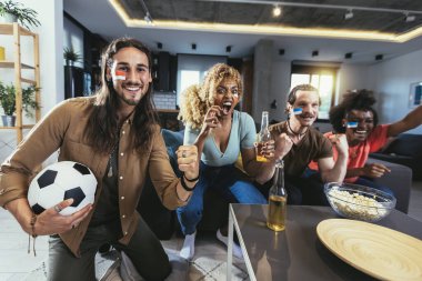 Genç bir grup televizyonda spor izliyor ve tezahürat yapıyor. Duygusal futbol hayranları evde futbol maçı izliyorlar. Boyalı Yüzlü Spor Hayranları TV 'de Kanepe İzleme Oyunu' nda oturuyor