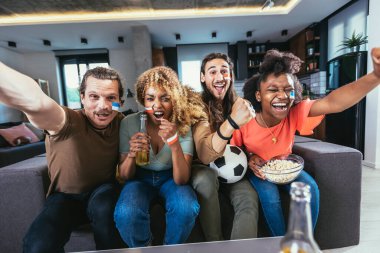 Genç bir grup televizyonda spor izliyor ve tezahürat yapıyor. Duygusal futbol hayranları evde futbol maçı izliyorlar. Boyalı Yüzlü Spor Hayranları TV 'de Kanepe İzleme Oyunu' nda oturuyor