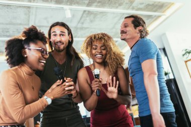 Group of young multicultural friends having party singing song using microphone at home.