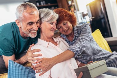 Bir grup orta yaşlı arkadaş doğum günü hediyelerini evde kutluyor.