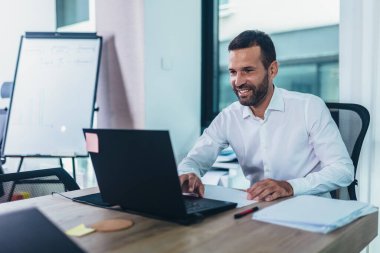 Dizüstü bilgisayar kullanarak Office onun masasında oturan genç adam portresi