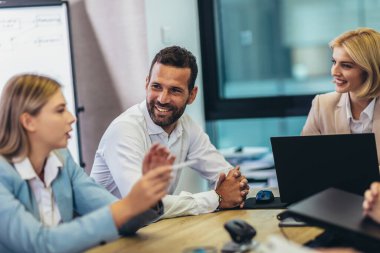 Office colleagues having discussion during meeting in conference room. Group of men and women sitting in conference room and smiling.