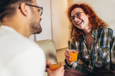 Mutlu genç çift kahvaltıda taze portakal suyunun tadını çıkarıyor.