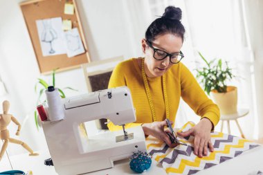 Evinde dikiş makinesine dikiş diken bir kadın. Dikiş makinesinde kadın terzilik işi