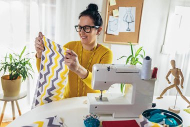 Evinde dikiş makinesine dikiş diken bir kadın. Dikiş makinesinde kadın terzilik işi