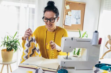 Evinde dikiş makinesine dikiş diken bir kadın. Dikiş makinesinde kadın terzilik işi
