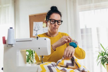 Evinde dikiş makinesine dikiş diken bir kadın. Dikiş makinesinde kadın terzilik işi