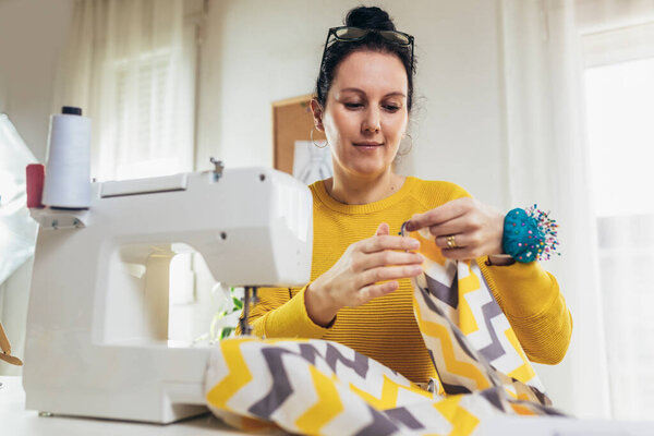 Женщина пришивает швейную машинку у себя дома. Женщина-швея работает на швейной машинке