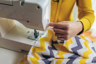 Evinde dikiş makinesine dikiş diken bir kadın..