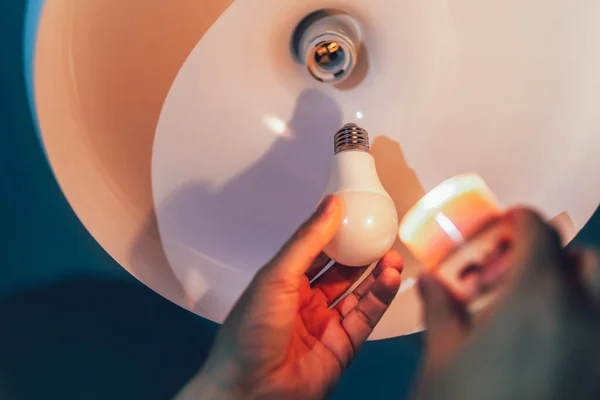 Man changing a light bulb in his home