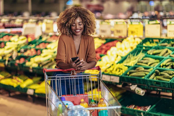 Donna Afroamericana Allegra Nel Supermercato Scegliere Spesa Fresca Utilizzando Telefono — Foto Stock