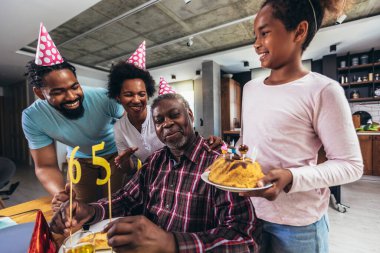 Multi-Generation african american family celebrating grandfathers birthday at home together