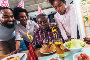 Multi-Generation african american family celebrating grandfathers birthday at home together