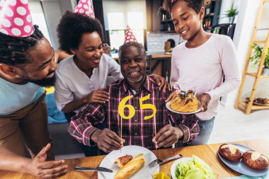 Multi-Generation african american family celebrating grandfathers birthday at home together