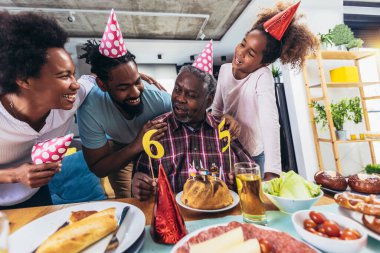 Multi-Generation african american family celebrating grandfathers birthday at home together