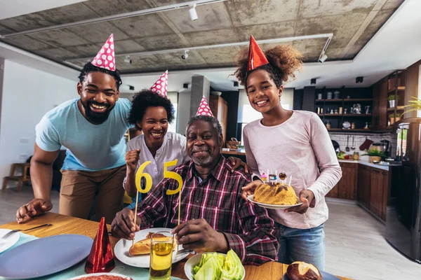 Multi-Generation african american family celebrating grandfathers birthday at home together