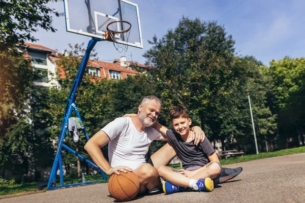 スポーツグラウンドでバスケットボールの試合を楽しむ父と息子 — ストック写真