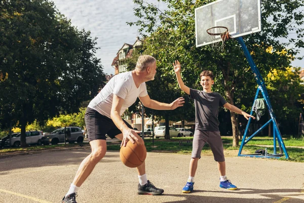 スポーツグラウンドでバスケットボールの試合を楽しむ父と息子 — ストック写真