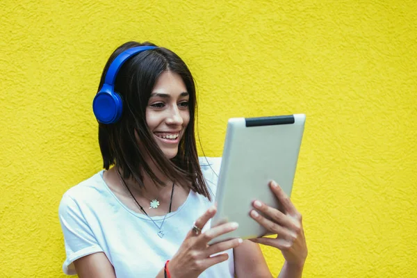 Молодая Женщина Слушает Музыку Цифровом Планшете Помощью Наушников Желтой Стене — стоковое фото