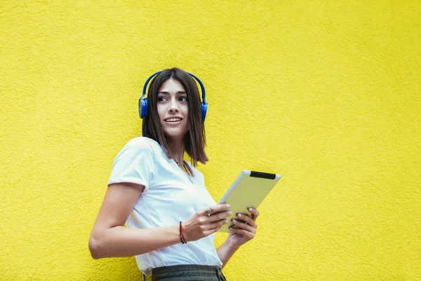 Ung Kvinna Lyssnar Musik Digital Surfplatta Med Hörlurar Gul Vägg — Stockfoto