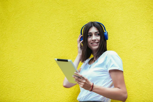 Ung Kvinna Lyssnar Musik Digital Surfplatta Med Hörlurar Gul Vägg — Stockfoto