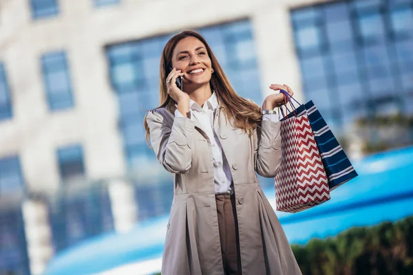 Şehirde Alışveriş Yaparken Cep Telefonunu Kullanan Çekici Genç Bir Kadın — Stok fotoğraf