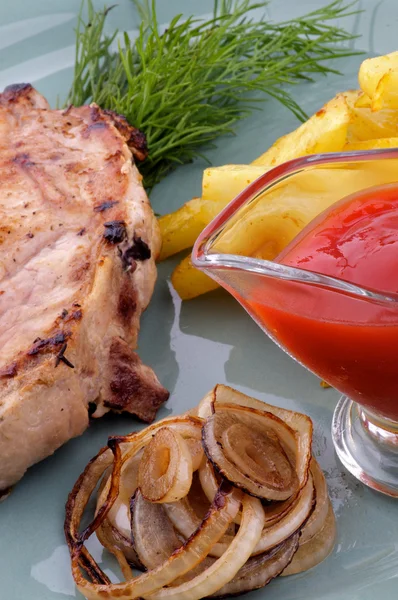 Bife de porco com batatas fritas e cebolas grelhadas — Fotografia de Stock