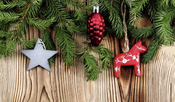 スプルースブランチの間に赤い馬 装飾コーンとシルバースターとクリスマスの装飾が木製の背景にクローズアップ — ストック写真