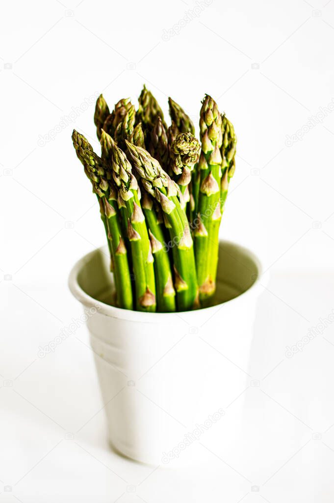 Perfect Raw Sprouts of Asparagus in White Pot isolated on White background