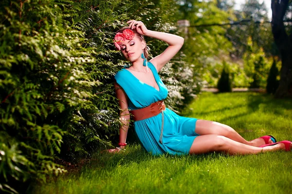 Žena v jasně modrých šatech pózuje venku sedí v zelené trávě — Stock fotografie