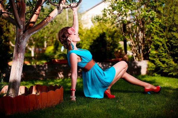 Açık havada yeşil çim oturarak poz parlak mavi elbiseli kadın — Stok fotoğraf