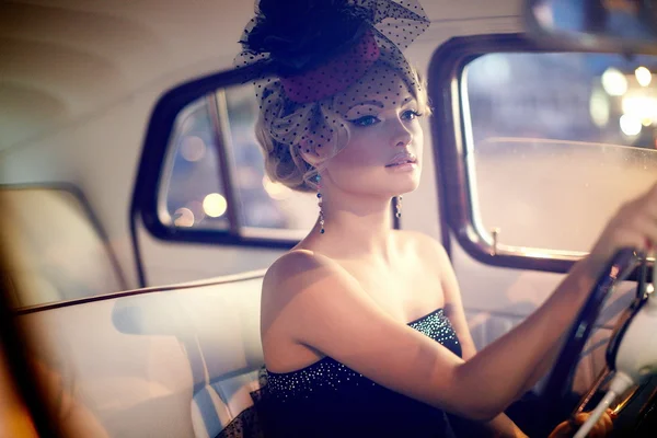 Vacker sexig kvinna sitter i gamla bil i retrostil Stockbild
