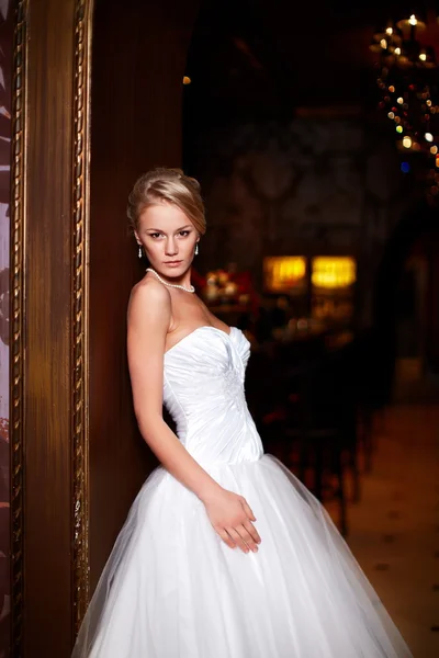 Gelukkig mooie sexy bruid blond meisje vrouw in witte bruiloft jurk met kapsel en lichte make-up in interieur — Stockfoto