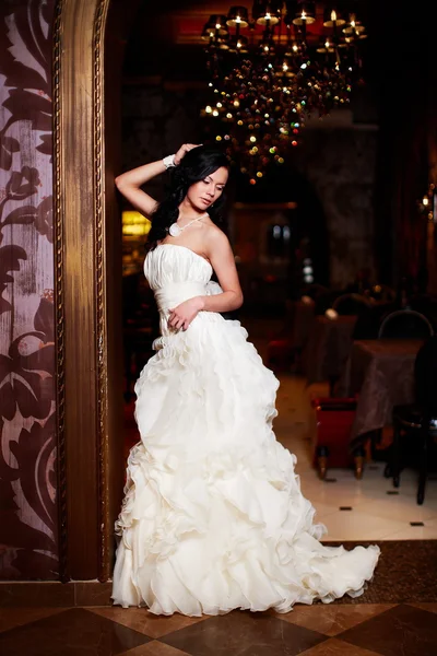 Feliz hermosa novia sexy chica morena mujer en vestido de novia blanco con peinado y maquillaje brillante en el interior — Foto de Stock