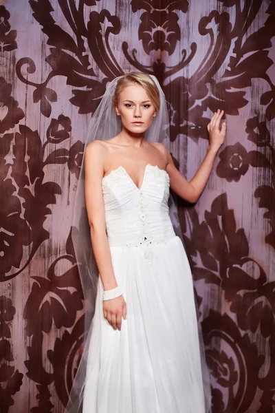 Gelukkig mooie sexy bruid blond meisje vrouw in witte bruiloft jurk met kapsel en lichte make-up in interieur — Stockfoto