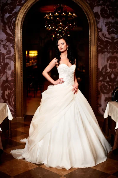 Felice bella sposa sexy ragazza bruna donna in abito da sposa bianco con acconciatura e trucco luminoso all'interno — Foto Stock