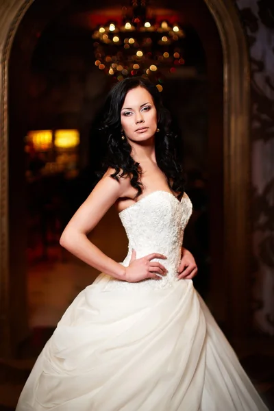 Joyeux belle mariée sexy fille brune femme en robe de mariée blanche avec coiffure et maquillage lumineux à l'intérieur — Photo