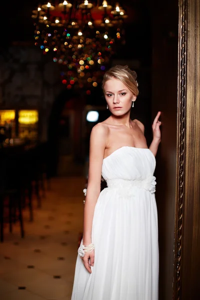 Joyeux belle mariée sexy blonde fille femme en robe de mariée blanche avec coiffure et maquillage lumineux à l'intérieur — Photo