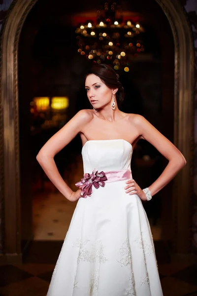 Glücklich schöne sexy Braut brünettes Mädchen Frau in weißem Hochzeitskleid mit Frisur und hellem Make-up im Inneren — Stockfoto