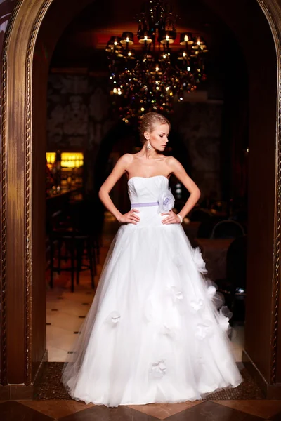 Joyeux belle mariée sexy blonde fille femme en robe de mariée blanche avec coiffure et maquillage lumineux à l'intérieur — Photo