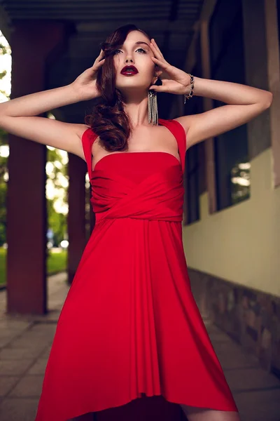 Elegante donna bruna con trucco luminoso in abito rosso — Foto Stock