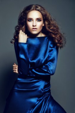 güzel seksi şık esmer beyaz genç kadın modeli Studio parlak mavi elbiseli sağlıklı kıvırcık saçlı parlak makyaj moda look.glamor portresi